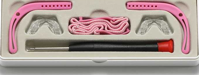 Storage tray with pink silicone ear hooks, spare nose pads, an eyewear cord and a fitting screwdriver
